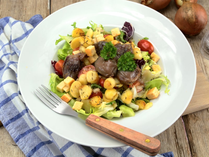 Salade de gésiers avec des croutons, des tomates cerise et des pommes de terre